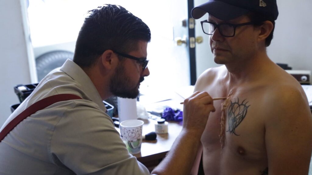 Jacob Whitley applying chest cut makeup effect on the set of Cadaver